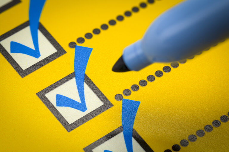 Yellow Checklist with Blue Marker Close Up.