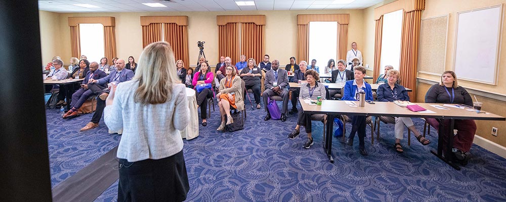 Woman giving presentation to a room full of people