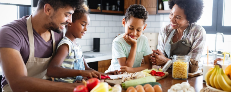 A family smiles around a kitchen counter