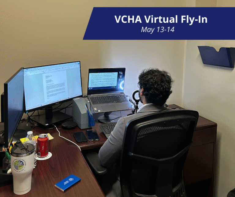 A man sits facing his desk on an online meeting with his back to the camera