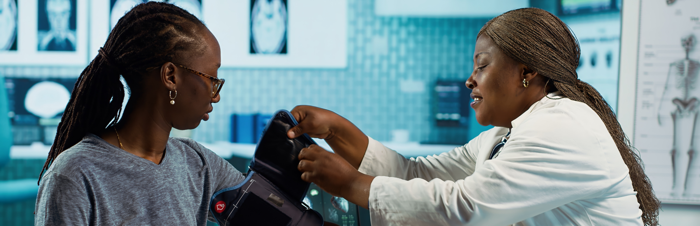 A Black female doctor checks the blood pressure of a Black female patient.
