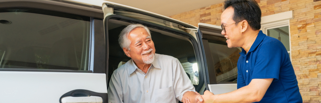 Asian man caregiver helps senior man patient get in the car to get to medical appointments