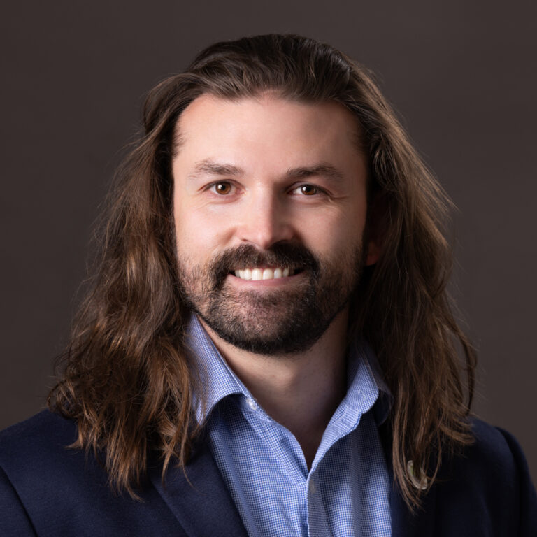 Headshot of Tyler Brown smiling, a white man with long brown hair.
