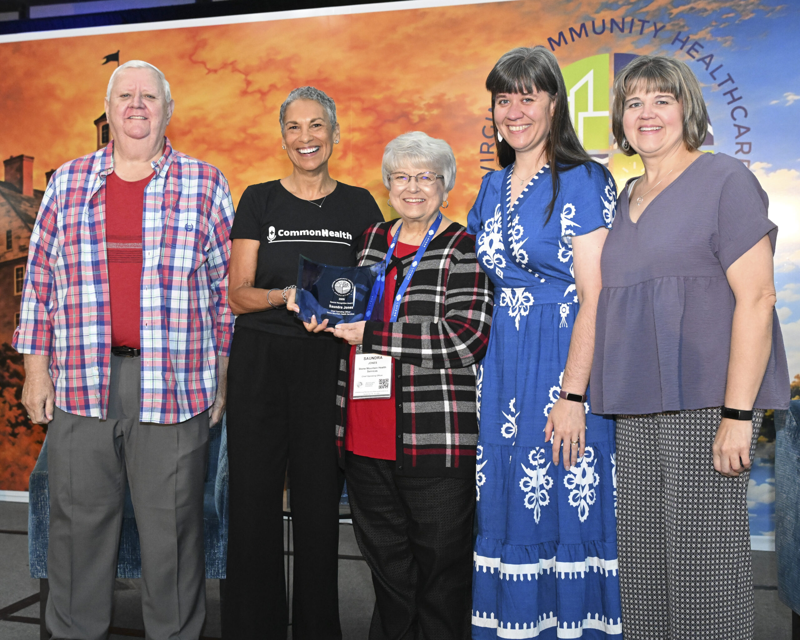 VCHA CEO Tracy Douglas, Saundra Jones, Chief Operating Officer at Stone Mountain Health Services, and Saundra's family, smile while holding the Special Recognition award