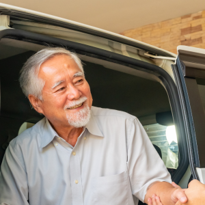Asian man caregiver helps senior man patient get in the car to get to medical appointments