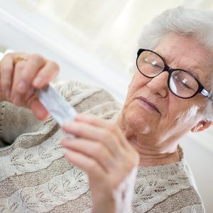 Close-up portrait of senior woman with glasses reading pill package